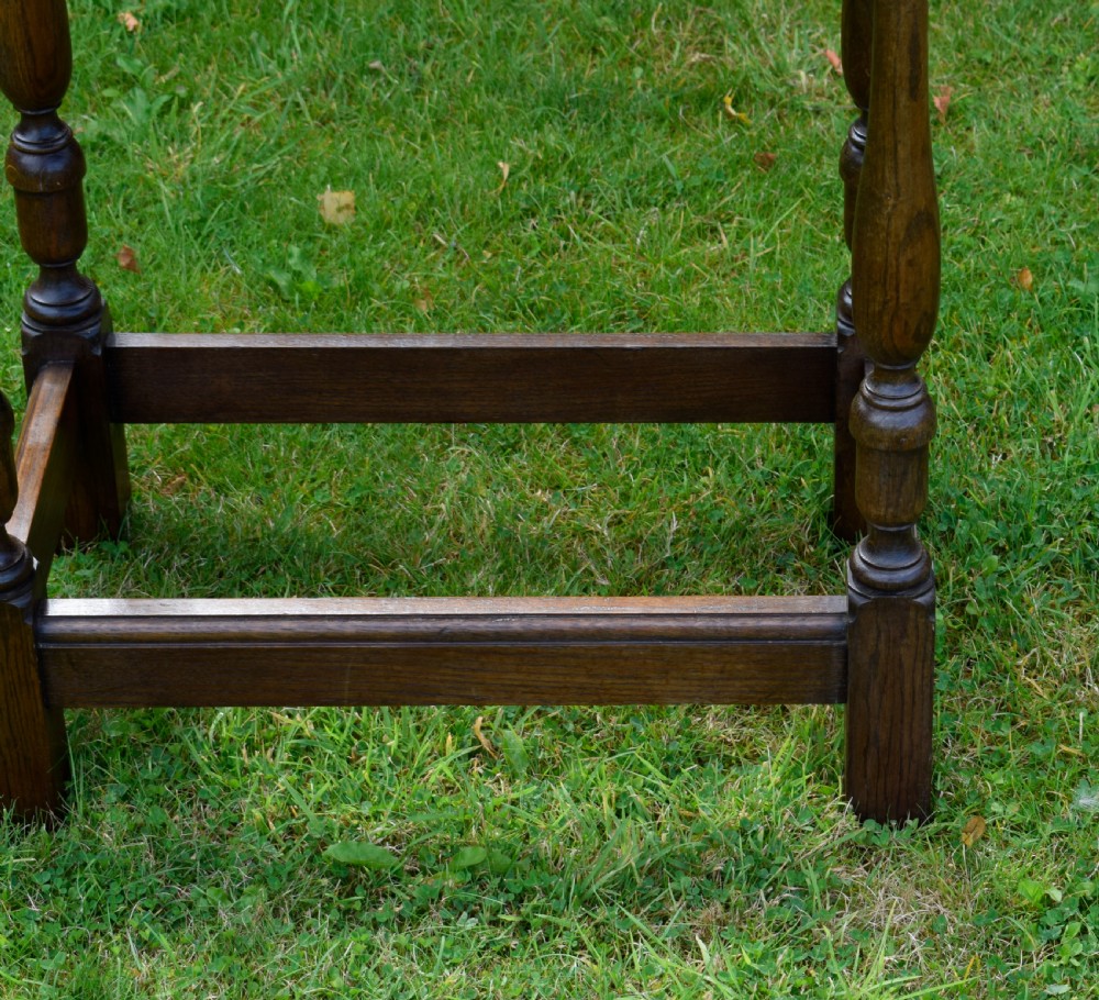 A tall rectangular dark oak side table featuring turned legs, a shaped apron, and lower perimeter box stretchers. View V