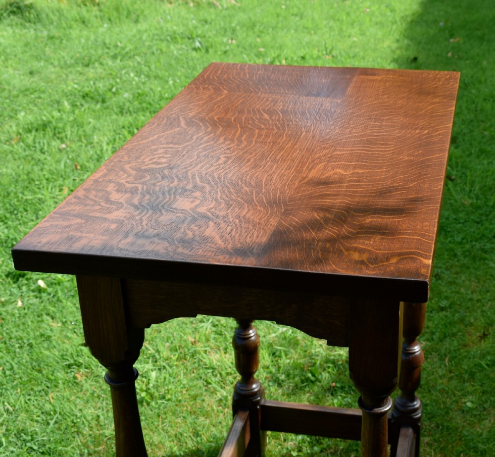 A tall rectangular dark oak side table featuring turned legs, a shaped apron, and lower perimeter box stretchers. View VII