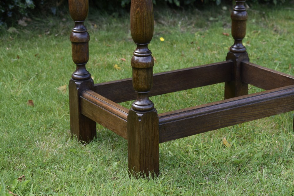 A tall rectangular dark oak side table featuring turned legs, a shaped apron, and lower perimeter box stretchers. View XII