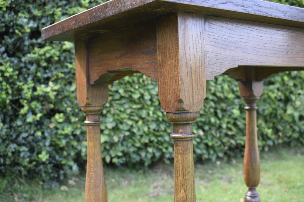 A tall rectangular dark oak side table featuring turned legs, a shaped apron, and lower perimeter box stretchers. View XIV
