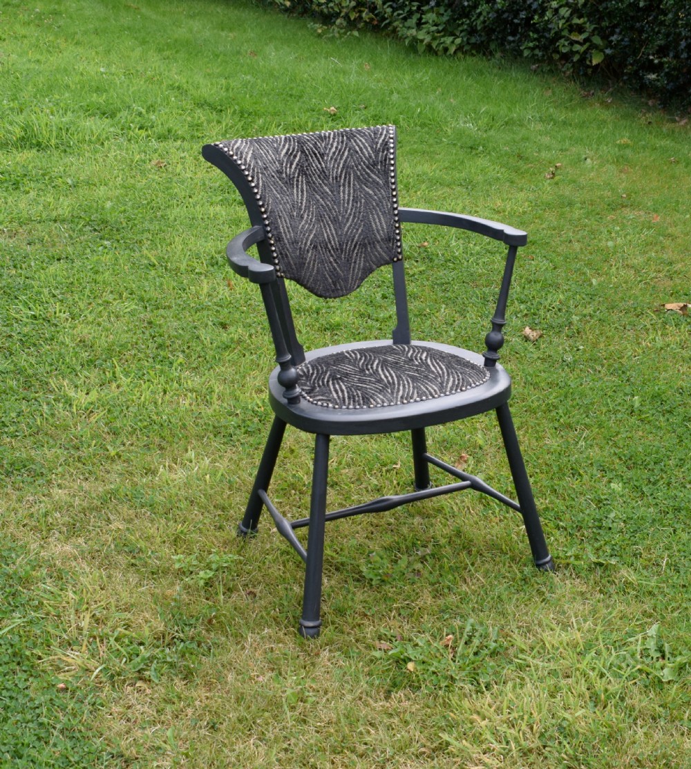 A dark grey painted Arts and Crafts style elbow chair featuring textured patterned fabric upholstery on the seat and curved backrest. View II