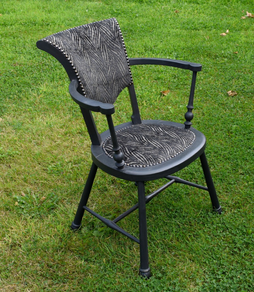 A dark grey painted Arts and Crafts style elbow chair featuring textured patterned fabric upholstery on the seat and curved backrest. View V