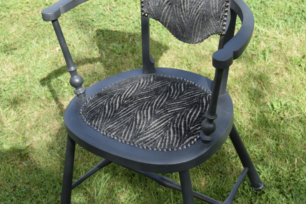 A dark grey painted Arts and Crafts style elbow chair featuring textured patterned fabric upholstery on the seat and curved backrest. View VIII