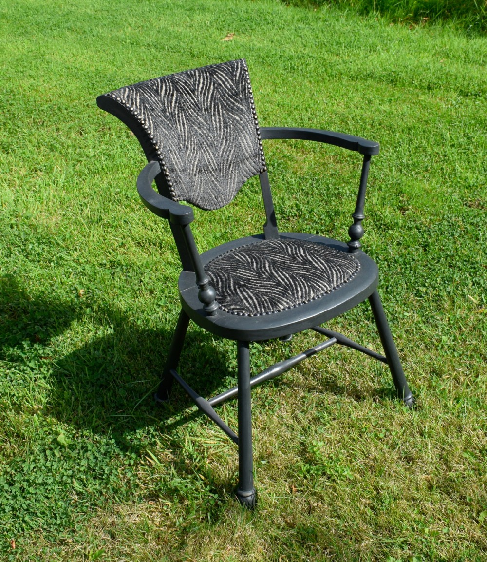 A dark grey painted Arts and Crafts style elbow chair featuring textured patterned fabric upholstery on the seat and curved backrest. View XI