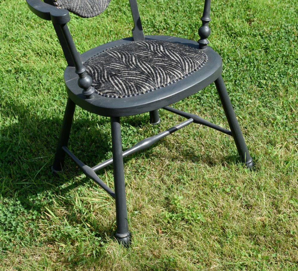 A dark grey painted Arts and Crafts style elbow chair featuring textured patterned fabric upholstery on the seat and curved backrest. View XII