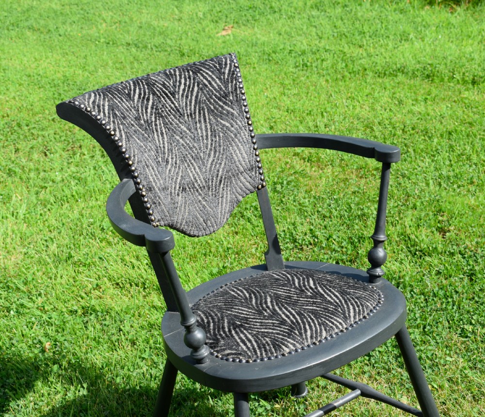 A dark grey painted Arts and Crafts style elbow chair featuring textured patterned fabric upholstery on the seat and curved backrest. View XIII