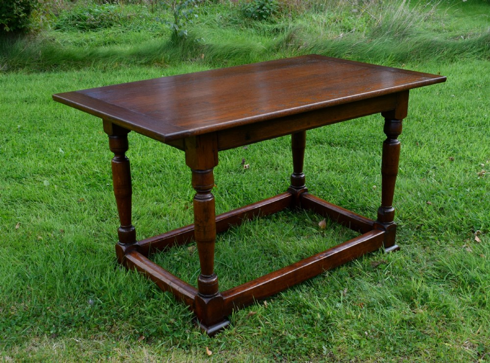 A rectangular dark oak refectory dining table featuring turned legs and a low perimeter stretcher base.