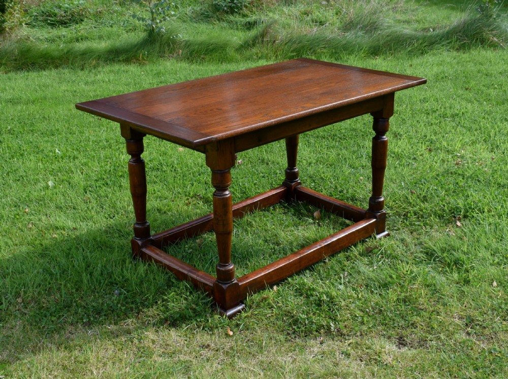 A rectangular dark oak refectory dining table featuring turned legs and a low perimeter stretcher base. View II