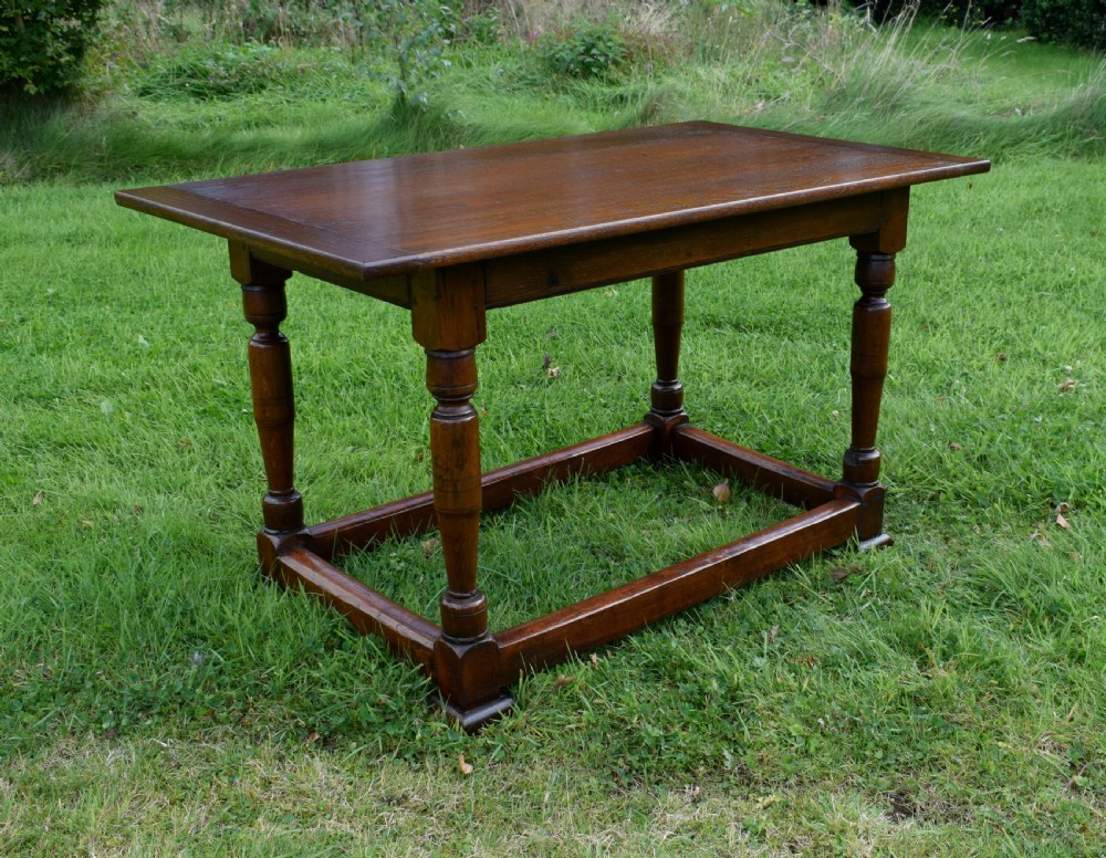 A rectangular dark oak refectory dining table featuring turned legs and a low perimeter stretcher base. View III