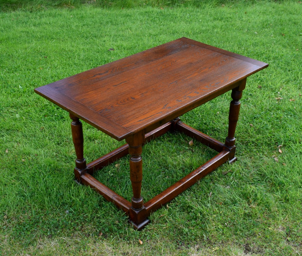 A rectangular dark oak refectory dining table featuring turned legs and a low perimeter stretcher base. View V