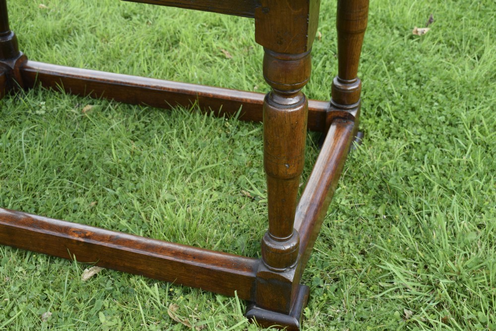 A rectangular dark oak refectory dining table featuring turned legs and a low perimeter stretcher base. View VI