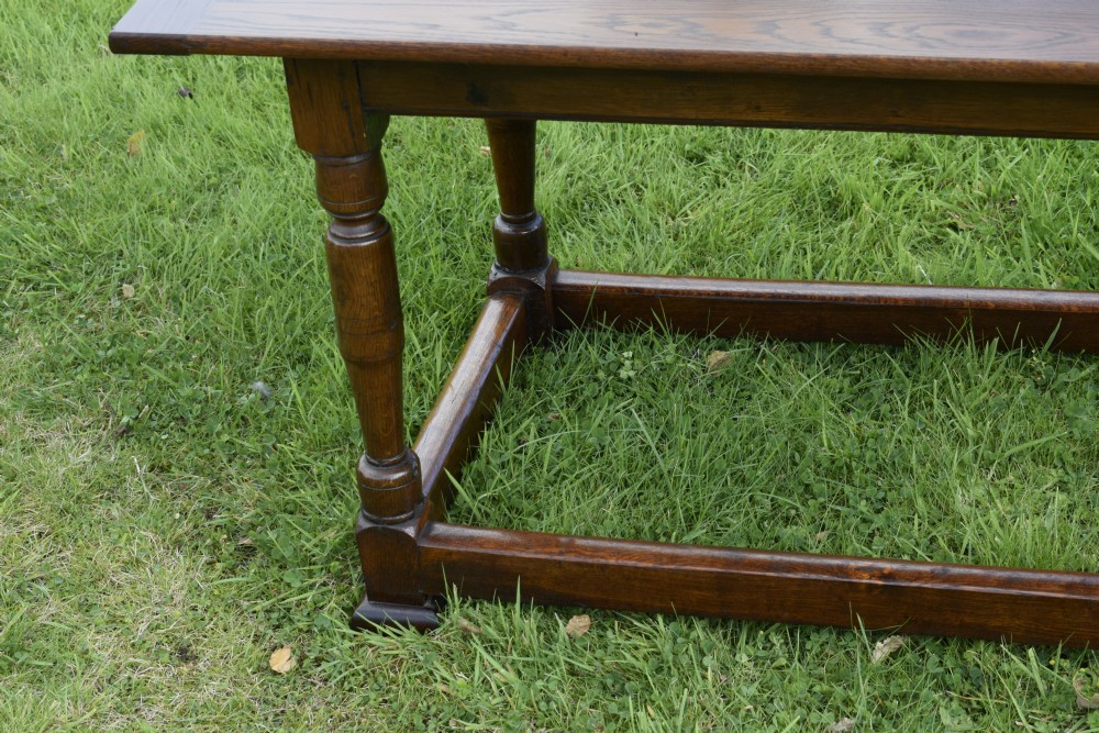 A rectangular dark oak refectory dining table featuring turned legs and a low perimeter stretcher base. View VII