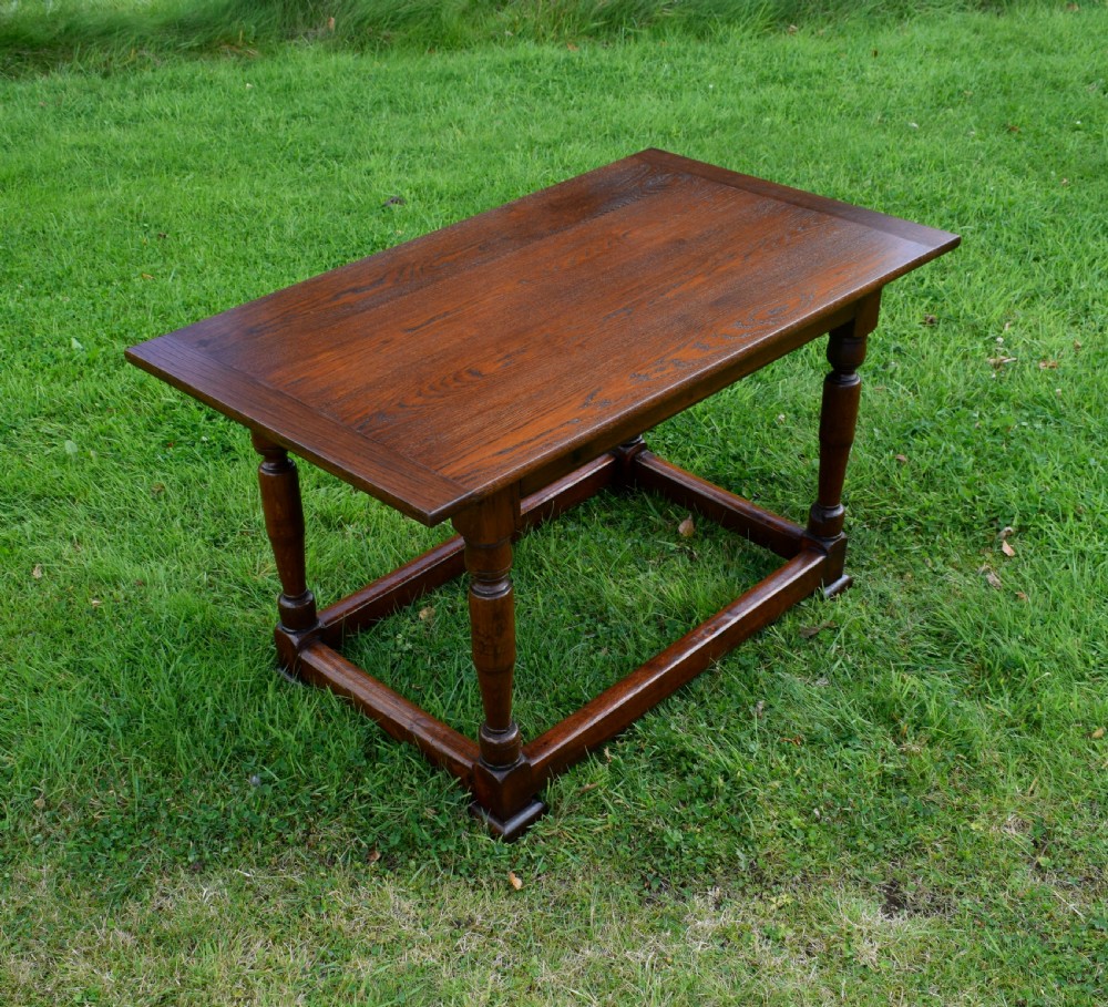 A rectangular dark oak refectory dining table featuring turned legs and a low perimeter stretcher base. View IX
