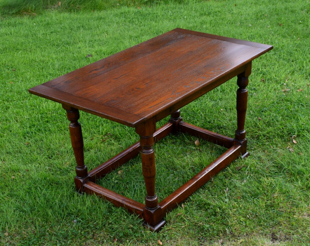 A rectangular dark oak refectory dining table featuring turned legs and a low perimeter stretcher base. View XI