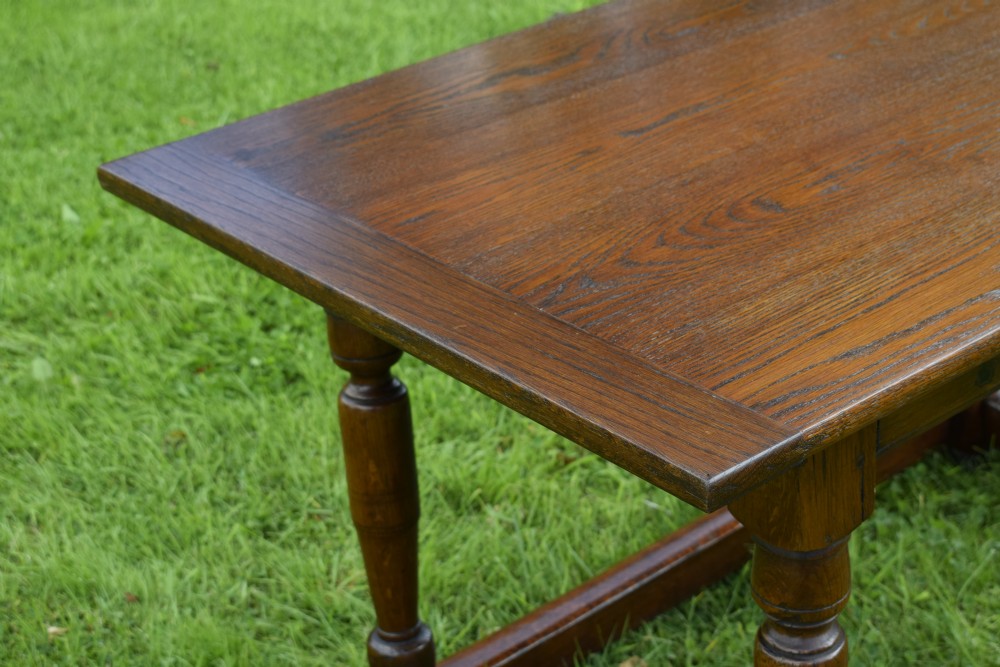 A rectangular dark oak refectory dining table featuring turned legs and a low perimeter stretcher base. View XII
