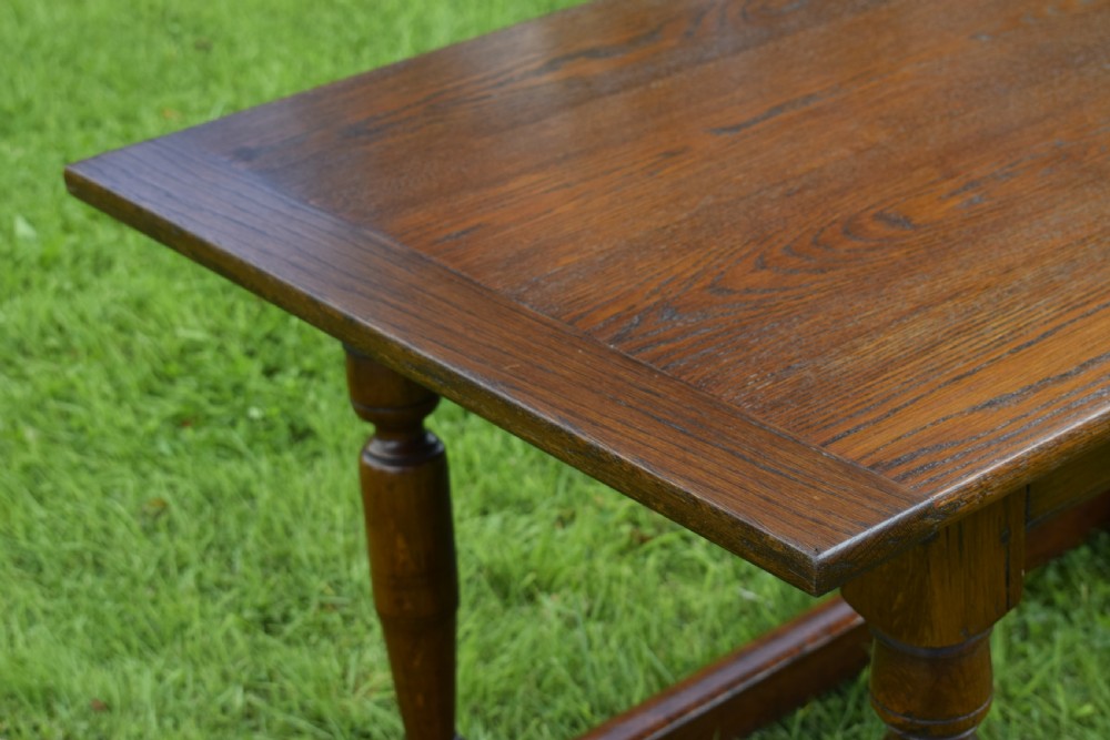 A rectangular dark oak refectory dining table featuring turned legs and a low perimeter stretcher base. View XIII