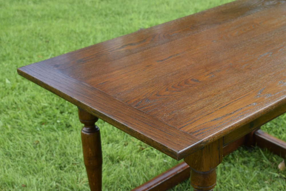 A rectangular dark oak refectory dining table featuring turned legs and a low perimeter stretcher base. View XVI