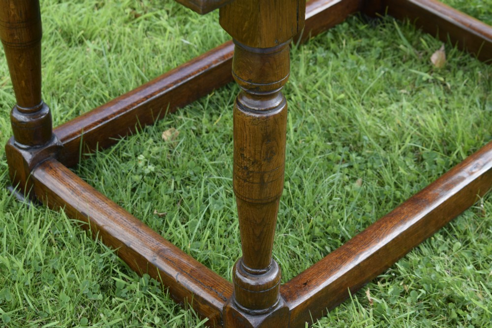 A rectangular dark oak refectory dining table featuring turned legs and a low perimeter stretcher base. View XVII