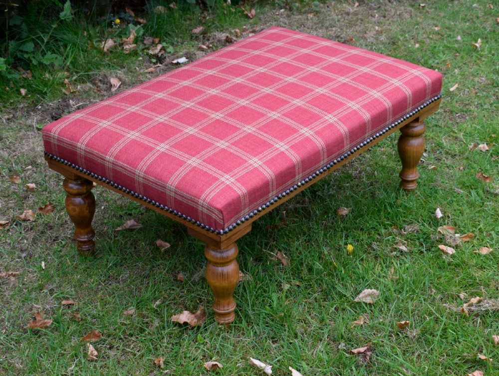 A large rectangular oak centre stool upholstered in red tartan fabric with turned legs and brass stud trimming. View II