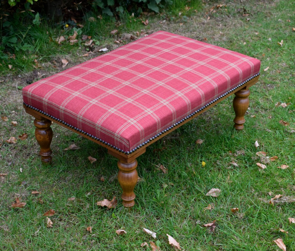 A large rectangular oak centre stool upholstered in red tartan fabric with turned legs and brass stud trimming. View V