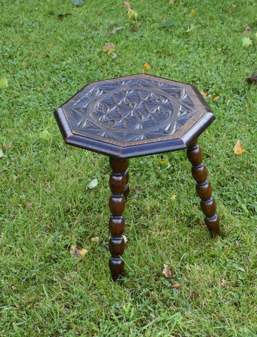 A dark stained wooden side table featuring an octagonal carved geometric top supported by three bobbin-turned legs. View II