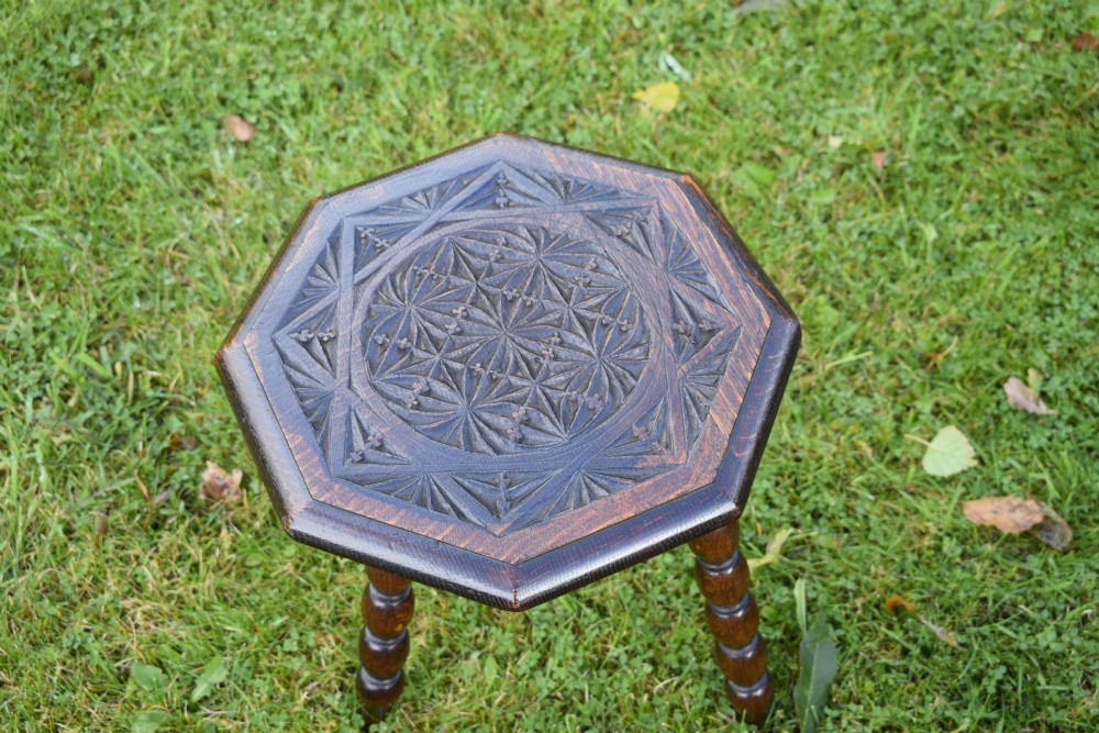 A dark stained wooden side table featuring an octagonal carved geometric top supported by three bobbin-turned legs. View VI