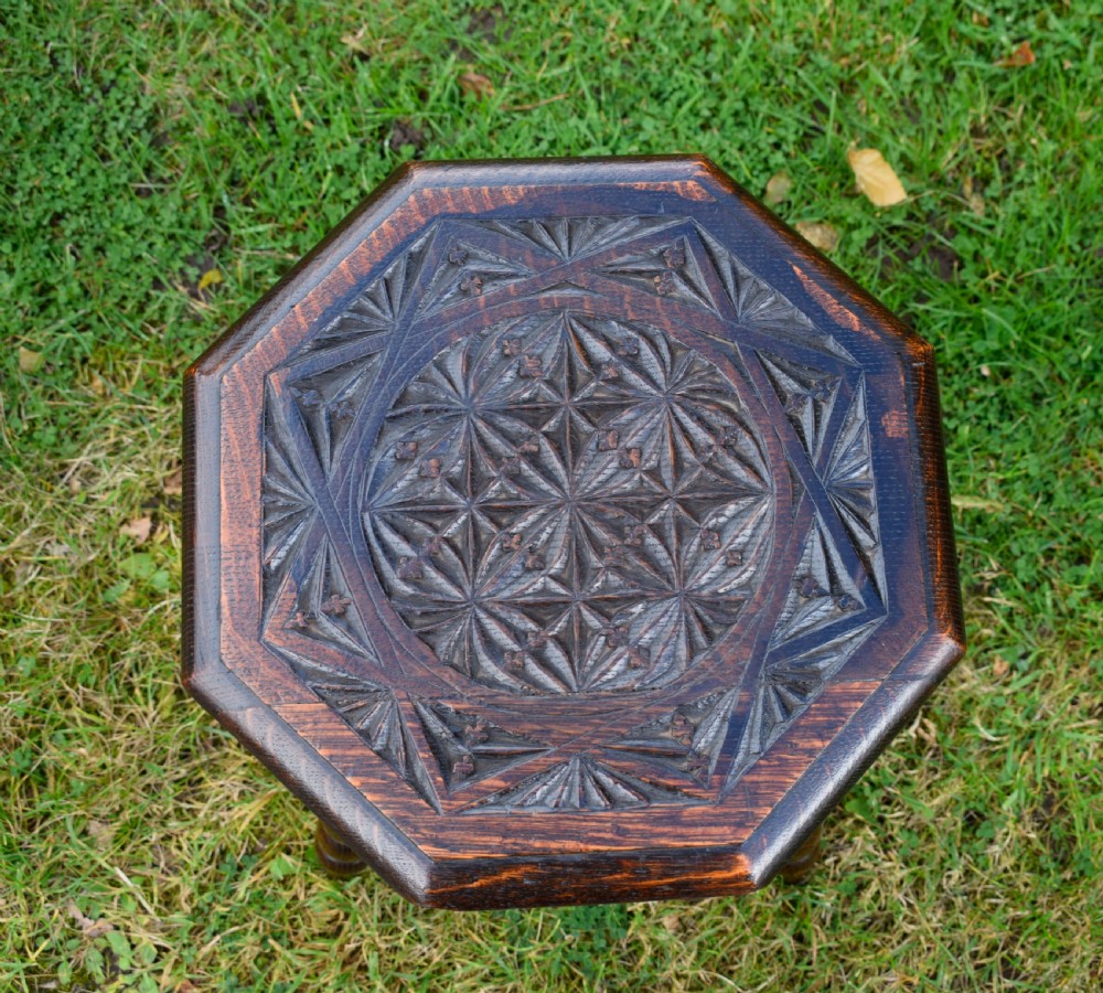 A dark stained wooden side table featuring an octagonal carved geometric top supported by three bobbin-turned legs. View VII