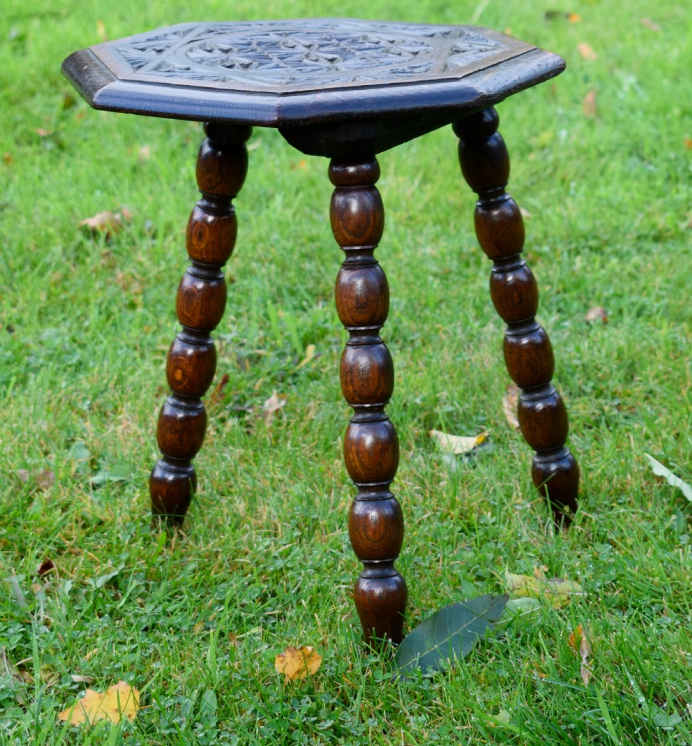 A dark stained wooden side table featuring an octagonal carved geometric top supported by three bobbin-turned legs. View IX