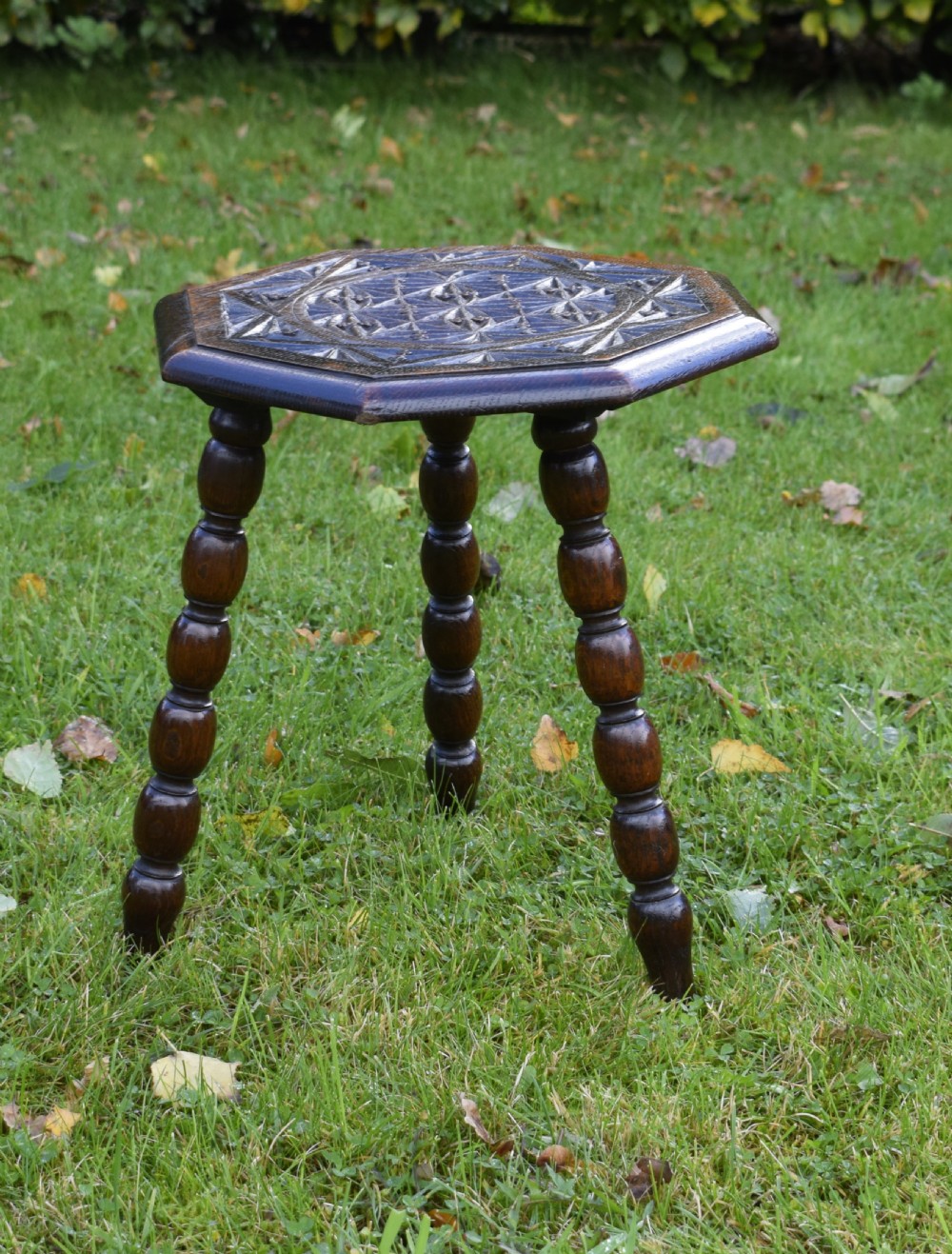 A dark stained wooden side table featuring an octagonal carved geometric top supported by three bobbin-turned legs. View XI