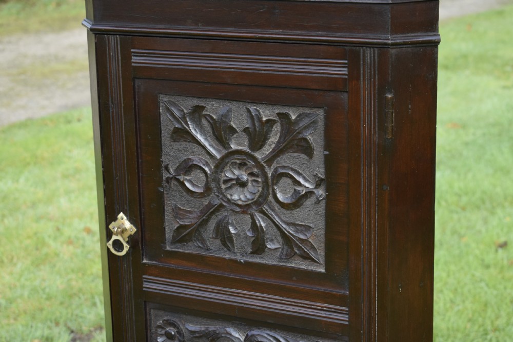 A dark-stained Victorian pine corner cupboard featuring hand-carved foliate panels, a moulded cornice, and a brass latch. View VIII