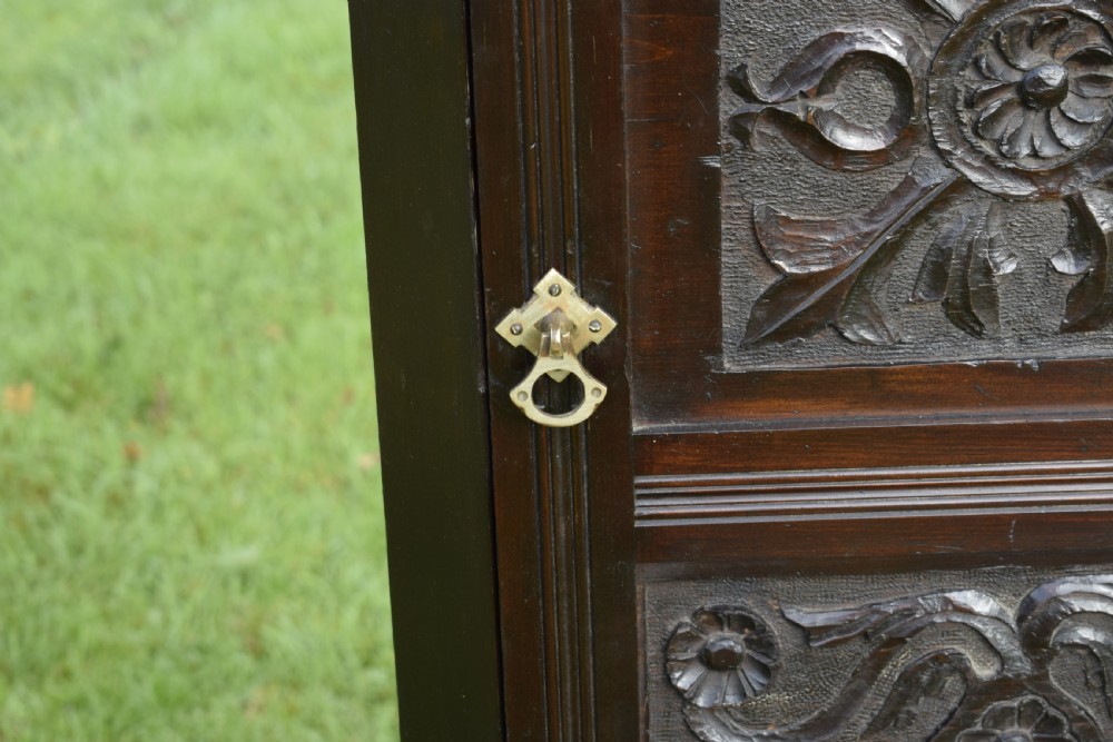 A dark-stained Victorian pine corner cupboard featuring hand-carved foliate panels, a moulded cornice, and a brass latch. View XIII