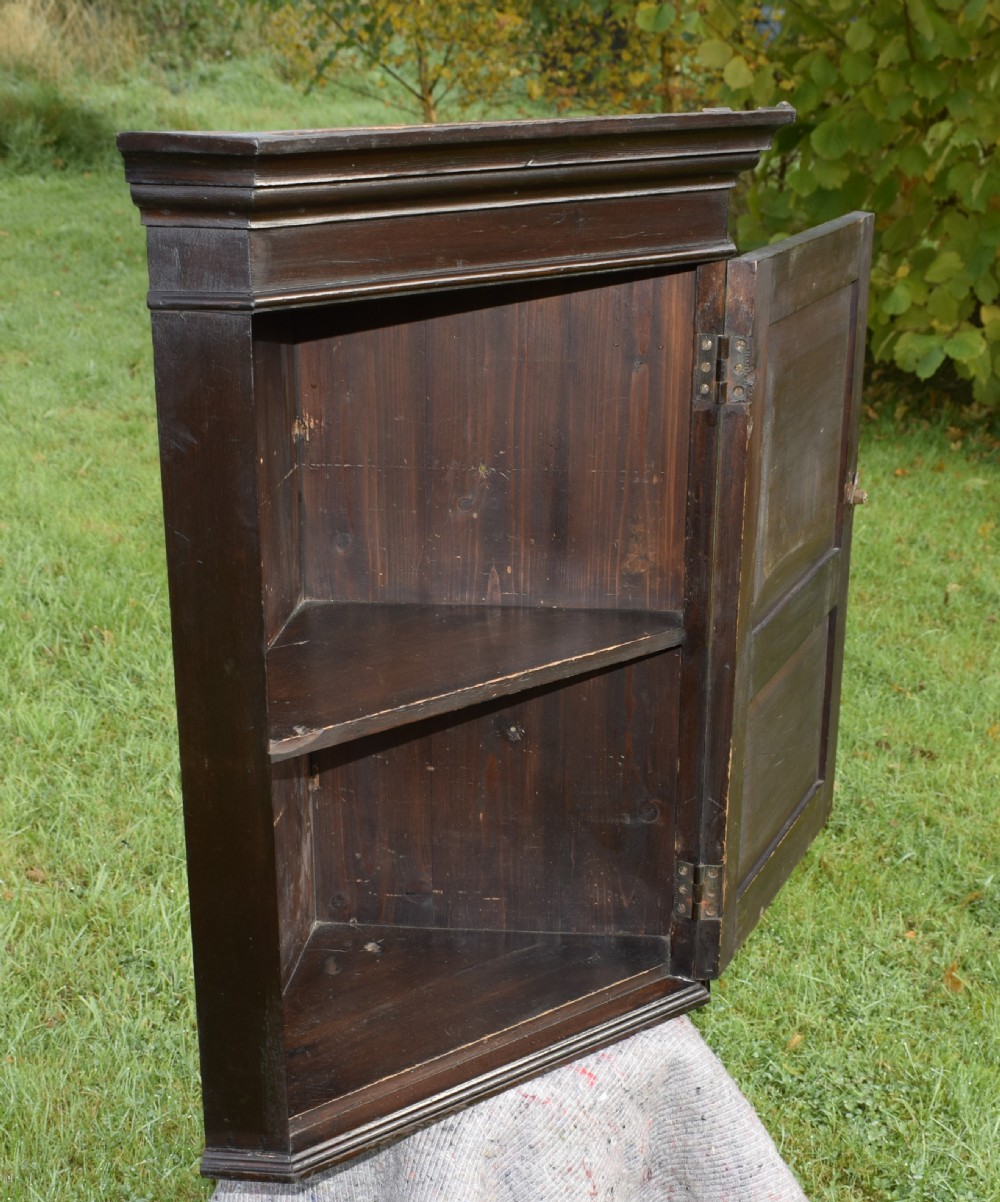 A dark-stained Victorian pine corner cupboard featuring hand-carved foliate panels, a moulded cornice, and a brass latch. View XIV