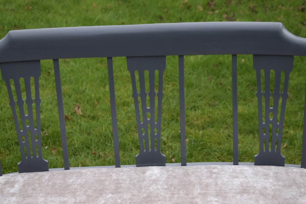An Edwardian painted grey wooden settee featuring vertical spindles, pierced back splats, and a neutral beige velvet upholstered seat. View X