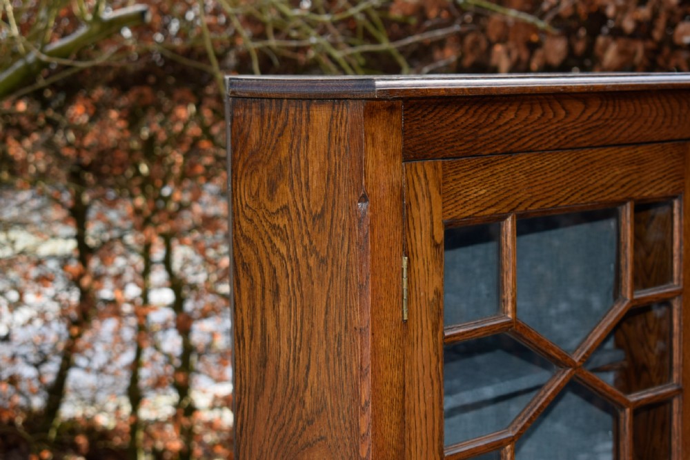An early twentieth-century freestanding oak corner cabinet featuring an upper astragal glazed door and a lower solid panelled door on bracket feet. View XIV