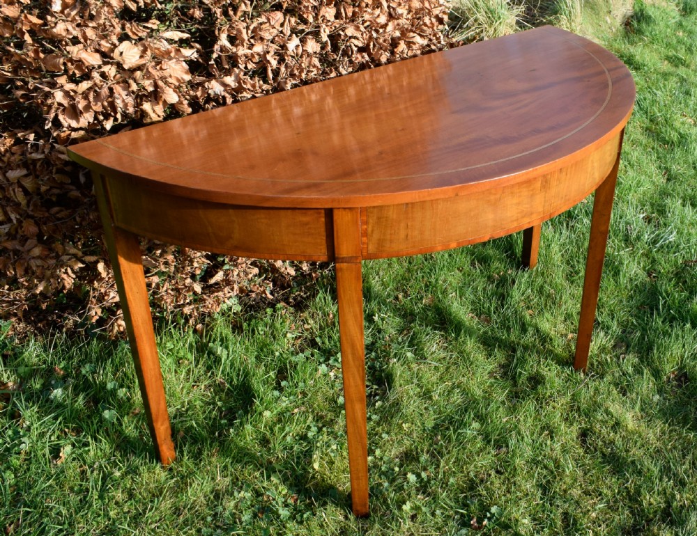 A Georgian mahogany demi-lune console table featuring a semi-circular top with string inlay and three tapered legs. View III