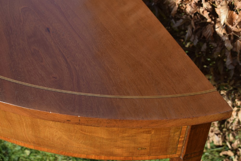 A Georgian mahogany demi-lune console table featuring a semi-circular top with string inlay and three tapered legs. View V