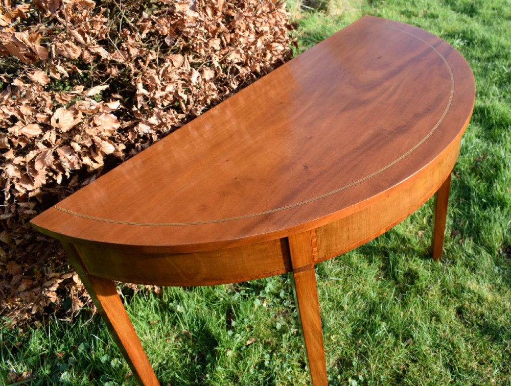 A Georgian mahogany demi-lune console table featuring a semi-circular top with string inlay and three tapered legs. View XII