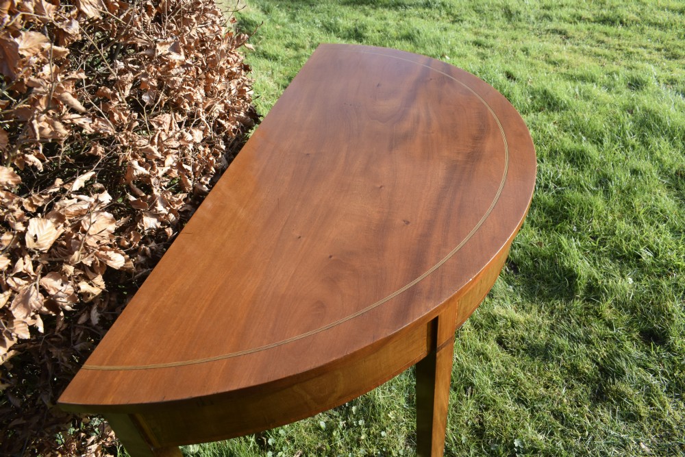 A Georgian mahogany demi-lune console table featuring a semi-circular top with string inlay and three tapered legs. View XIV