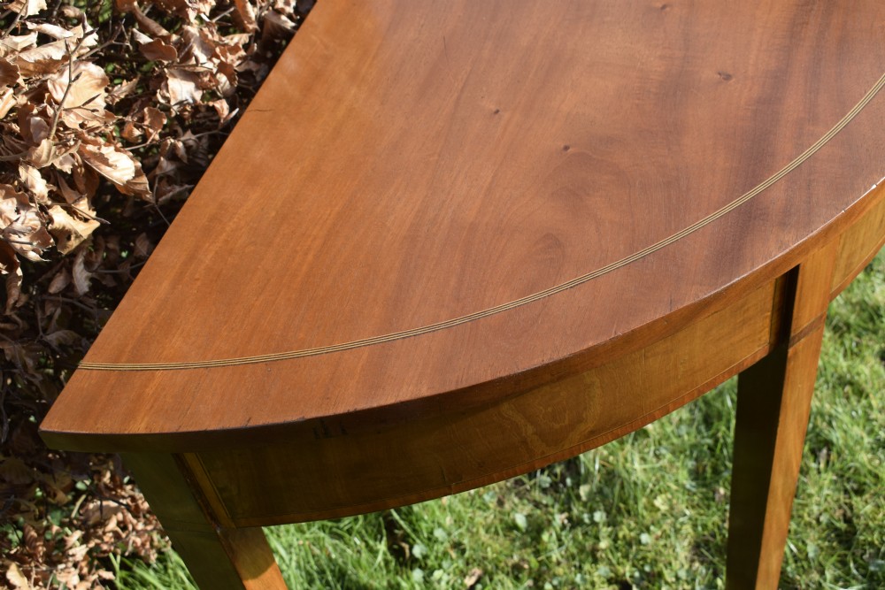 A Georgian mahogany demi-lune console table featuring a semi-circular top with string inlay and three tapered legs. View XV