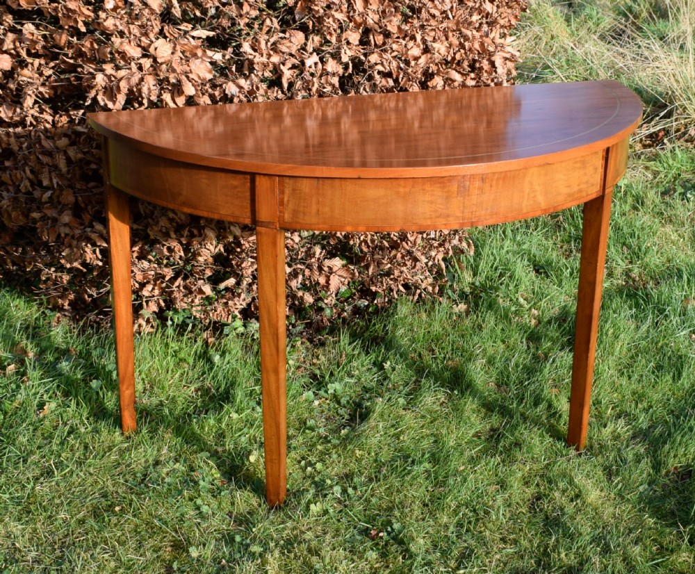 A Georgian mahogany demi-lune console table featuring a semi-circular top with string inlay and three tapered legs. View XVI