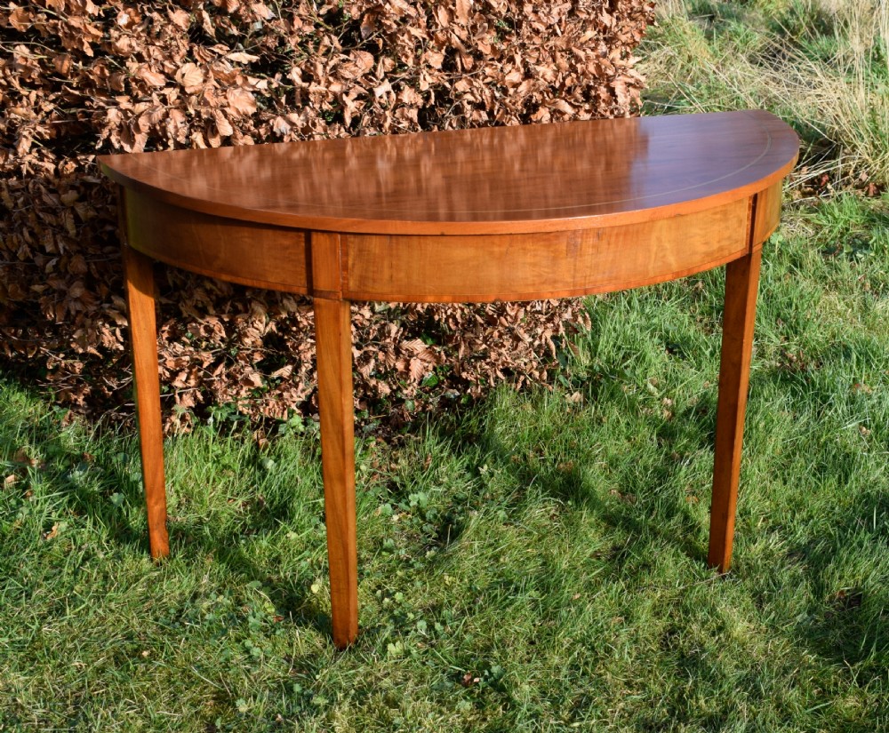A Georgian mahogany demi-lune console table featuring a semi-circular top with string inlay and three tapered legs. View XVII