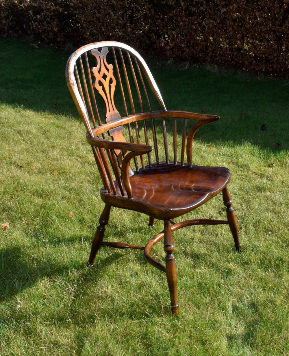 An antique dark wood Windsor armchair featuring a hoop back, pierced central splat, turned legs, and a shaped seat. View II