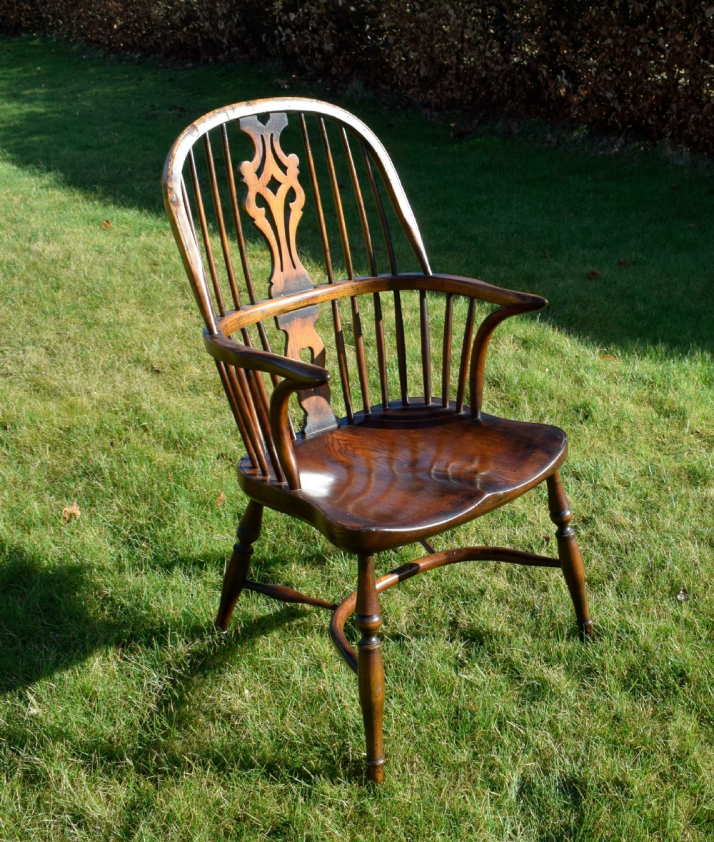 An antique dark wood Windsor armchair featuring a hoop back, pierced central splat, turned legs, and a shaped seat. View VI