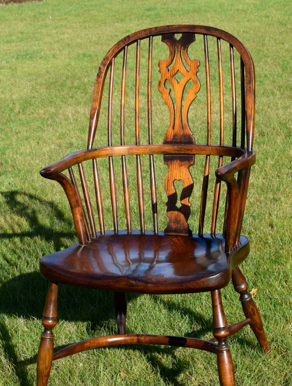 An antique dark wood Windsor armchair featuring a hoop back, pierced central splat, turned legs, and a shaped seat. View VII