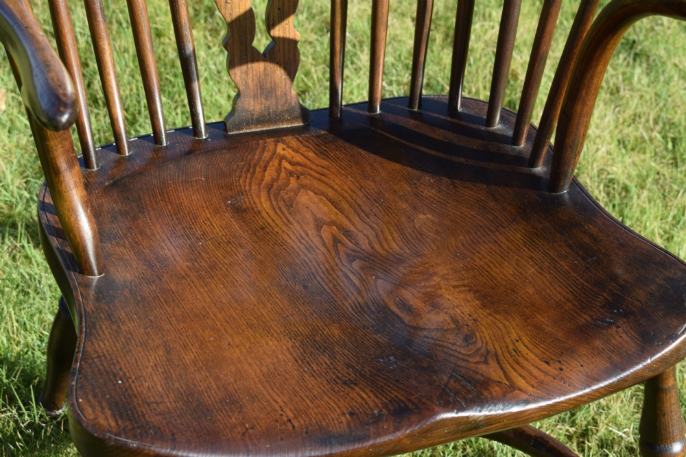 An antique dark wood Windsor armchair featuring a hoop back, pierced central splat, turned legs, and a shaped seat. View VIII