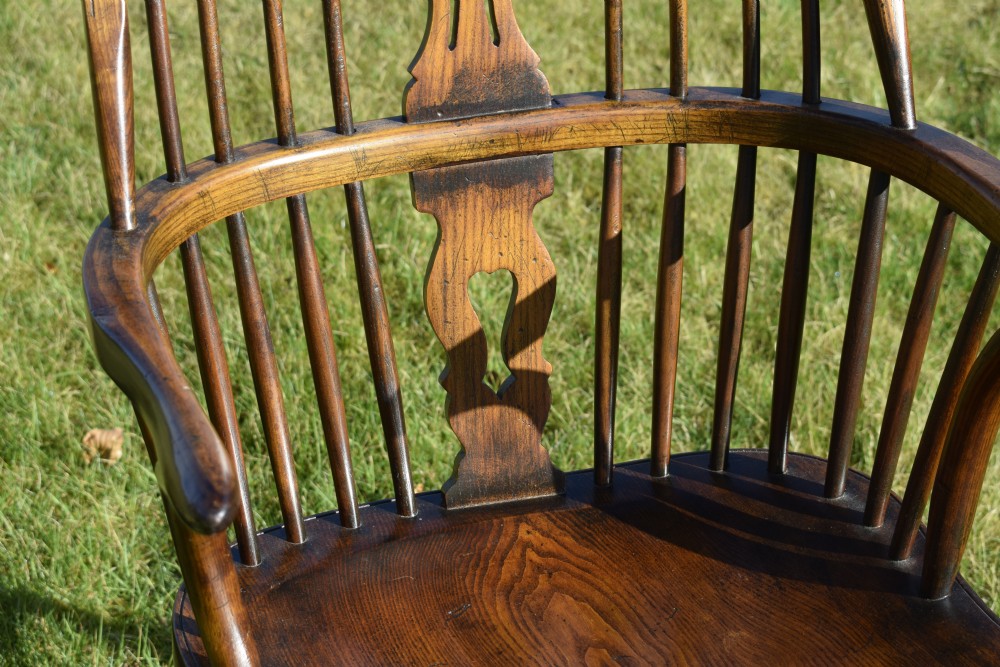 An antique dark wood Windsor armchair featuring a hoop back, pierced central splat, turned legs, and a shaped seat. View IX