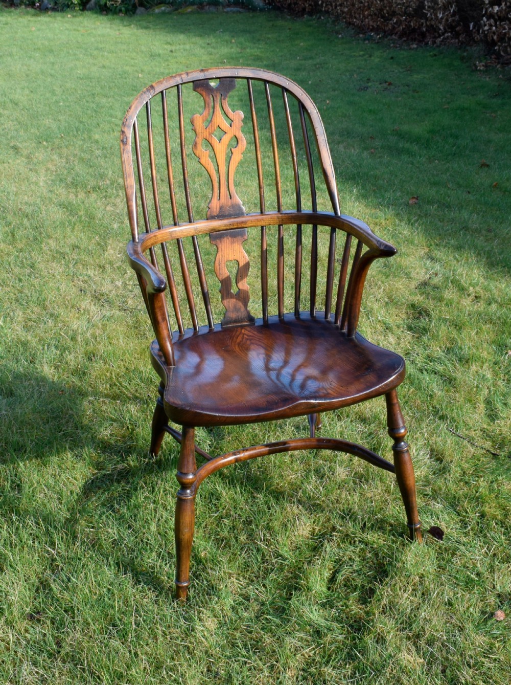 An antique dark wood Windsor armchair featuring a hoop back, pierced central splat, turned legs, and a shaped seat. View XI