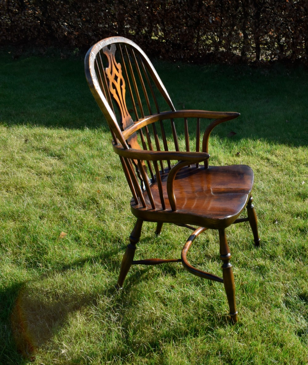 An antique dark wood Windsor armchair featuring a hoop back, pierced central splat, turned legs, and a shaped seat. View XIII