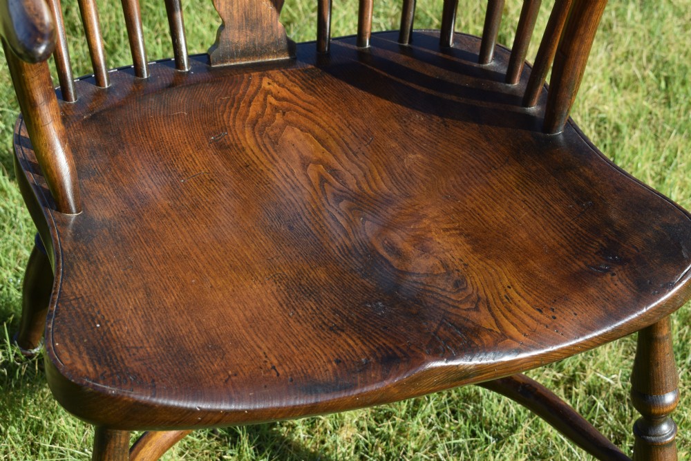 An antique dark wood Windsor armchair featuring a hoop back, pierced central splat, turned legs, and a shaped seat. View XVII