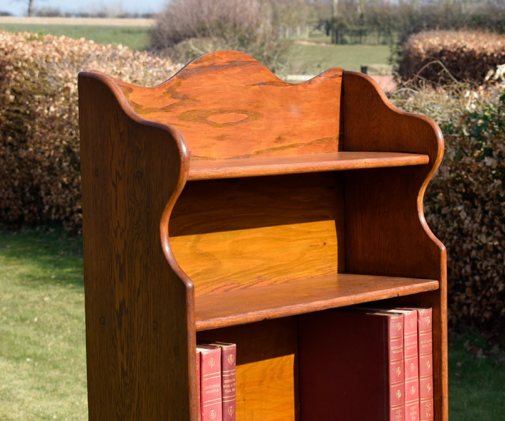 A tall early 20th-century open-front oak bookcase featuring four fixed shelves and a shaped top gallery. View III